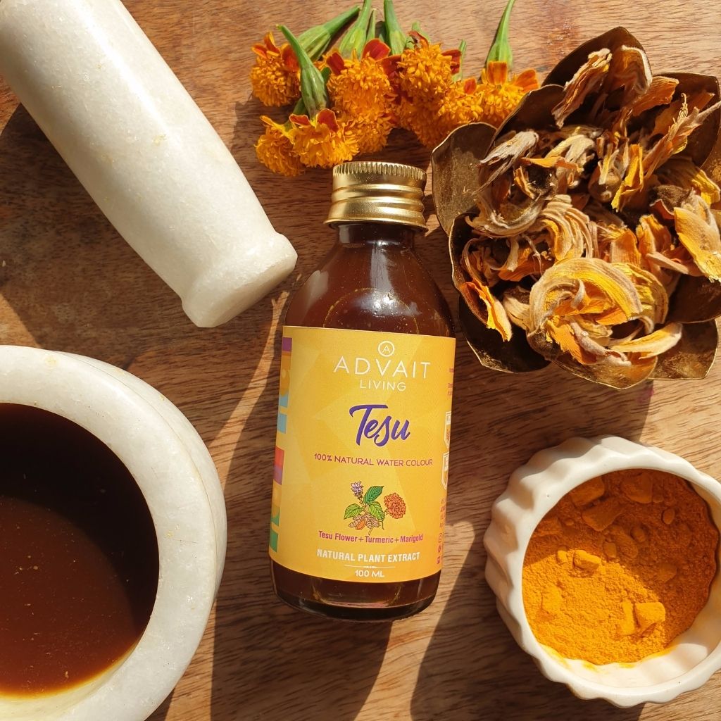 A bottle of tesu water colour, tesu flowers and a bowl containing the liquid.