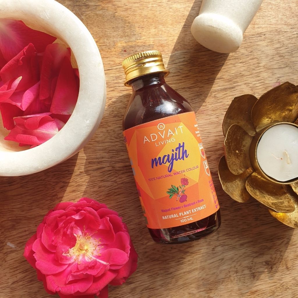 A bottle of Majith water colour with roses on a table.