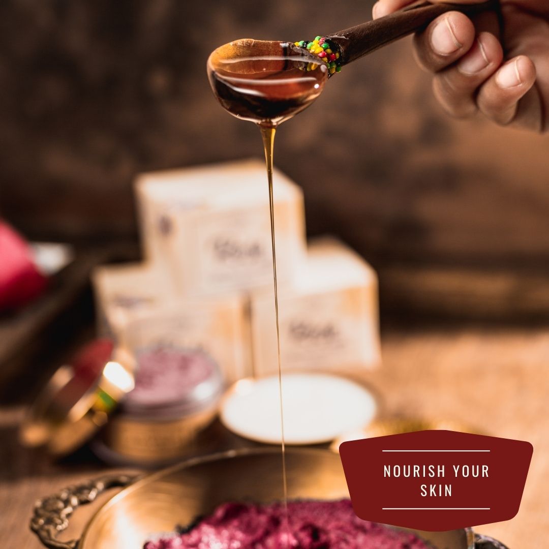 honey dripping from wooden spoon held mid air