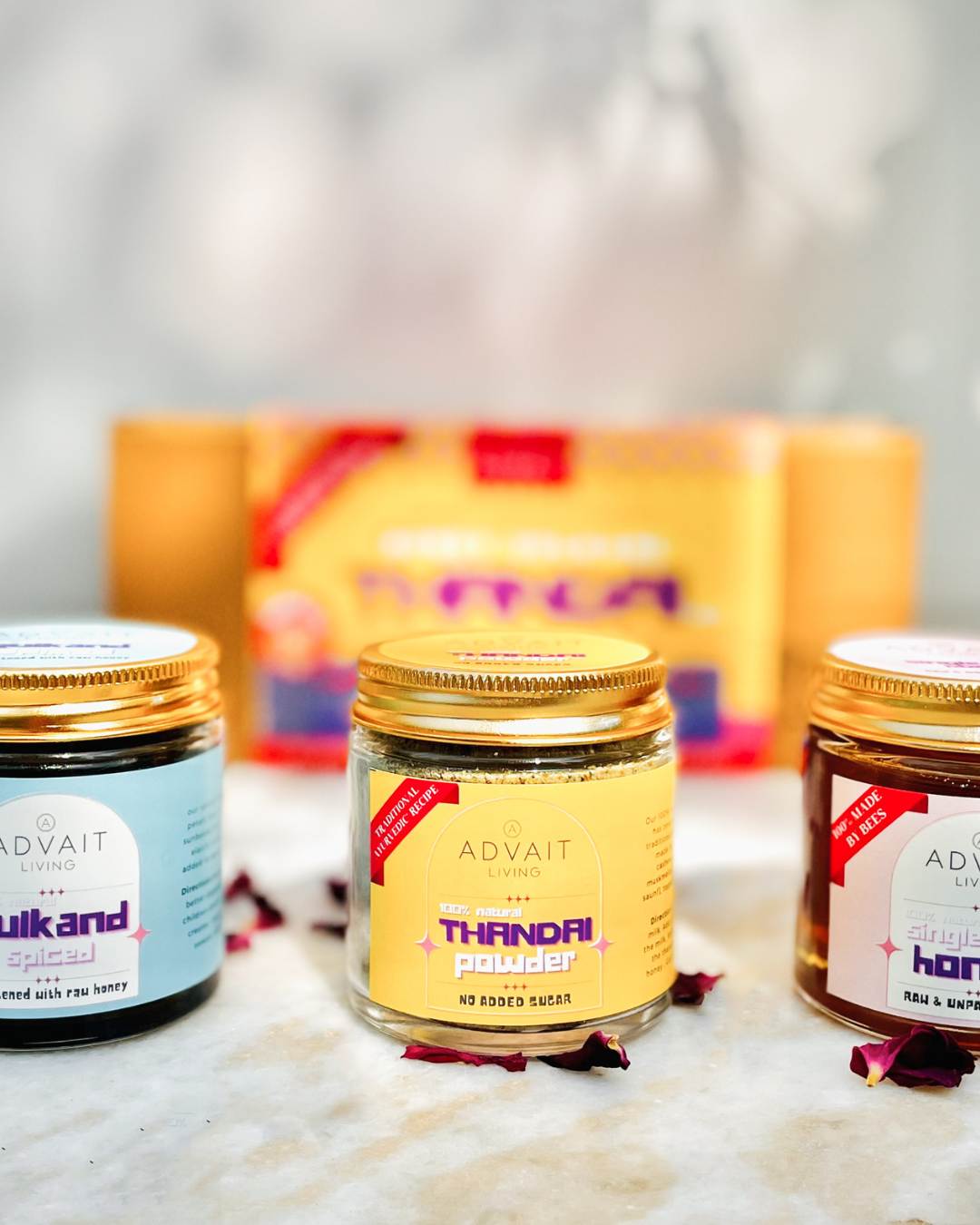 Glass jar of Advait Living Sugar-free Thandai powder placed in between a jar of spiced honey gulkand and single flora honey.